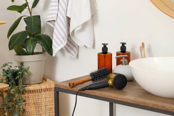 Cepillo redondo con secador de pelo en la mesa en el baño, primer plano - Foto, imagen