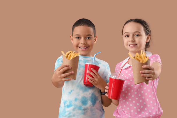 フランスのフライドポテトと茶色の背景にコーラのカップを持つ幸せな小さな子供たち - 写真・画像