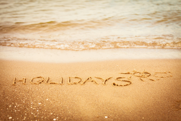 The word holidays written in the sand on a beach - Fotó, kép