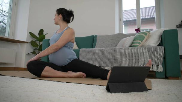 Rutina de estiramiento posterior al embarazo en etapa tardía: la mujer embarazada de 30 años prioriza el bienestar con ejercicios suaves en el hogar, mejorando la salud corporal y el confort - Foto, Imagen
