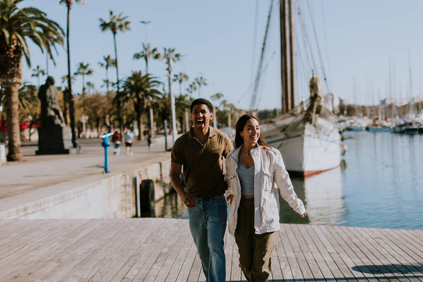 Cuple cieszy się spokojnym spacerem obok zacumowanych łodzi w Barcelonie spokojnej przystani, pławiąc się w miękkim świetle poranka. - Zdjęcie, obraz