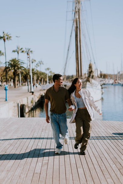 Cuple cieszy się spokojnym spacerem obok zacumowanych łodzi w Barcelonie spokojnej przystani, pławiąc się w miękkim świetle poranka. - Zdjęcie, obraz