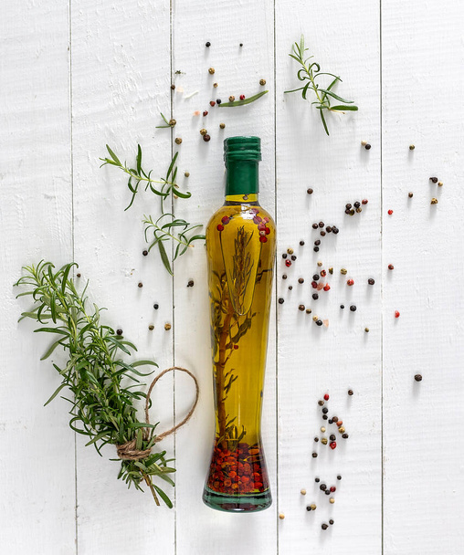 Fresh olives and oil in bottle with rosemary on a white wooden background  - Photo, Image