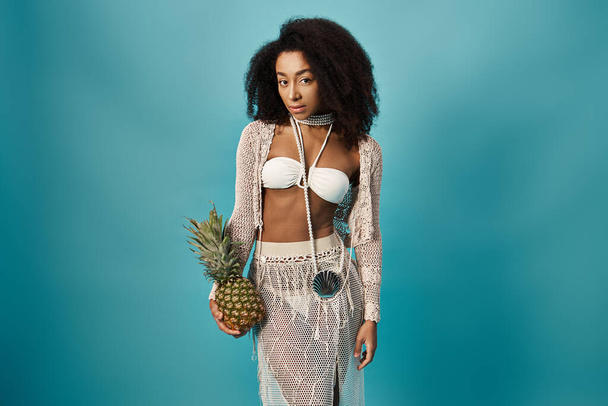 Stylish young African American woman in bikini holding a pineapple. - Photo, Image