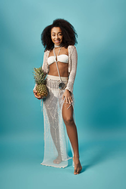 Elegant woman in white swimsuit gracefully holding a pineapple. - Photo, Image