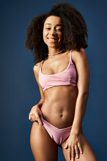 Νεαρή Αφροαμερικανή που ποζάρει με αυτοπεποίθηση σε μοντέρνο ροζ μπικίνι. - Φωτογραφία, εικόνα