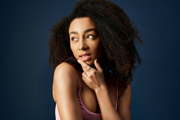Woman with curly hairdo striking a thoughtful pose with hand on chin. - Photo, Image