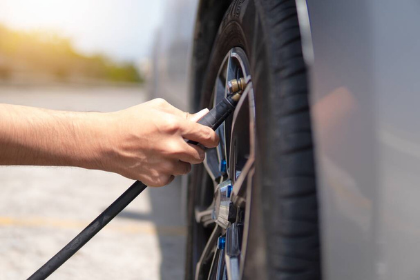 Nahaufnahme eines Mannes, der Reifen aufpumpt und Luft in die Reifen seines Autos füllt. - Foto, Bild