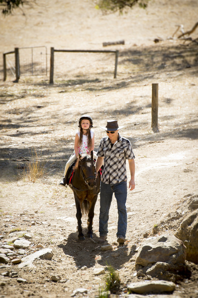 Junger Jockey beim Ponyreiten im Freien glücklich mit Vaterrolle als Reitlehrer im Cowboy-Look - Foto, Bild