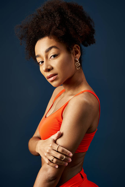 Stílusos fiatal afro-amerikai nő pózol magabiztosan színes narancs felső. - Fotó, kép