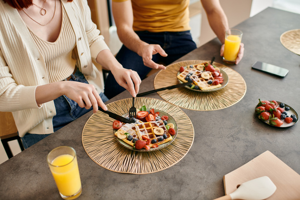 テーブルに座って,モダンなアパートで一緒に朝食を楽しむカップル. - 写真・画像