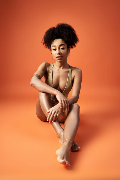 African American woman in stylish bikini, striking a pose on vibrant orange backdrop. - Photo, Image