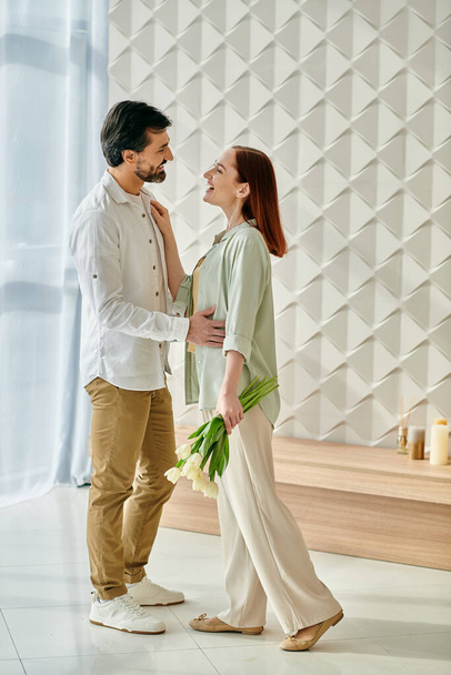 Um homem barbudo e uma mulher ruiva estão juntos em um apartamento moderno, exalando amor e conexão. - Foto, Imagem