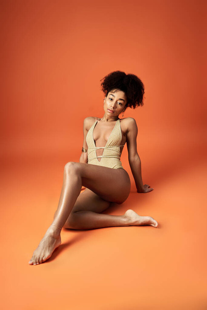 Afroamerykanka w modnym bikini na pomarańczowym tle. - Zdjęcie, obraz