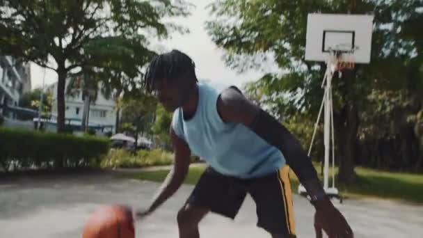 Портативный снимок двух афроамериканских спортсменов, играющих в стритбол на детской площадке на открытом воздухе - Кадры, видео