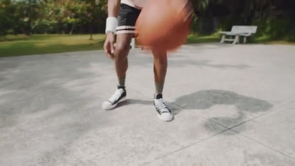 Colpo palmare del giocatore maschio nero che rimbalza palla sul pavimento durante la partita di streetball con un amico sul campo all'aperto - Filmati, video
