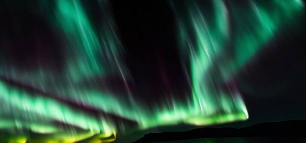 Aurora australis or Aurora borealis or Green northern lights sky above mountains. Night sky with polar lights. Night winter landscape with southern lights aurora against Real Natural black background. - Photo, Image