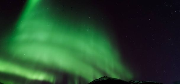 Aurora australis or Aurora borealis or Green northern lights sky above mountains. Night sky with polar lights. Night winter landscape with southern lights aurora against Real Natural black background. - Photo, Image