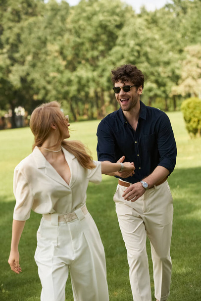 A beautiful young couple in elegant clothing enjoying a leisurely walk through a green park, embodying an old-money luxurious lifestyle. - Photo, Image