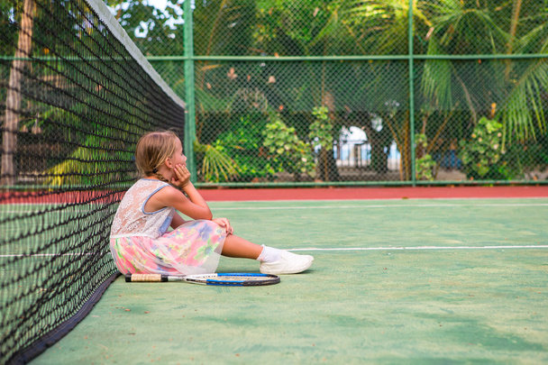 Маленькая девочка играет в теннис на корте
 - Фото, изображение