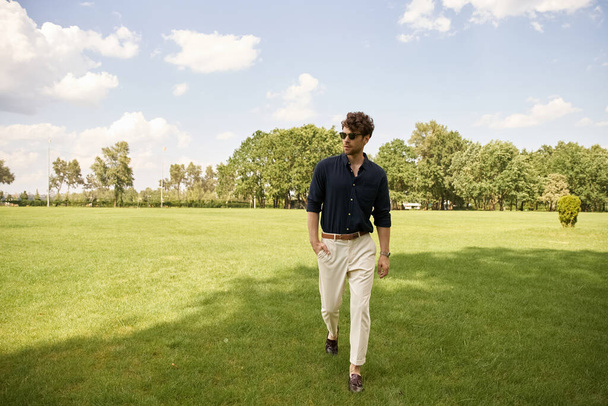 Чоловік прогулюється крізь пишне трав'яне поле під чистим небом, занурюючись у спокій і спокій природи. - Фото, зображення