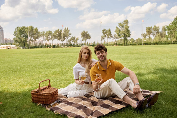 Tyylikäs pari tyylikkäässä puvussa nauttimassa ylellisestä piknikistä puistossa vihreällä kentällä. - Valokuva, kuva