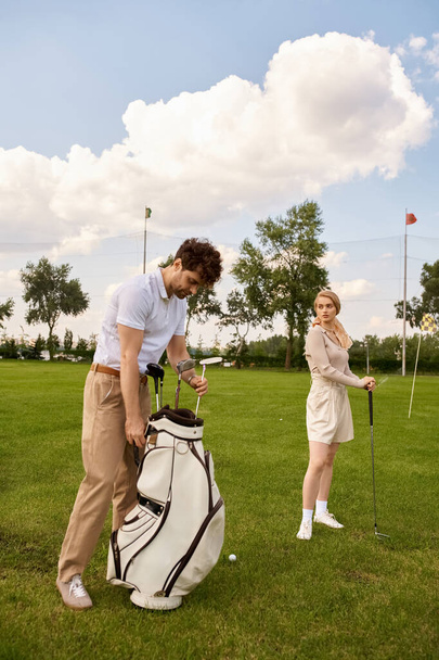 Un hombre y una mujer en traje elegante de pie juntos en un campo de golf verde exuberante, rodeado de lujo y sofisticación. - Foto, imagen