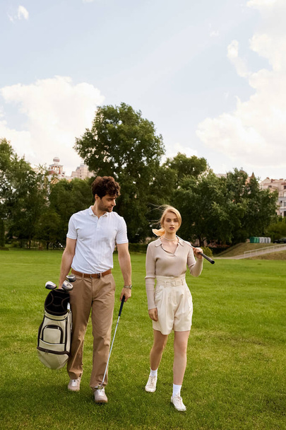 Een stijlvol koppel in elegante kledij die samen wandelen op een weelderige groene golfbaan onder de open hemel. - Foto, afbeelding