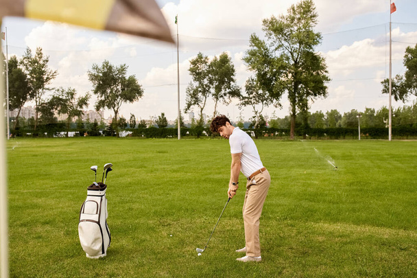 Un hombre en traje elegante golpea una pelota de golf en un campo verde exuberante, mostrando gracia y sofisticación en el viejo estilo de dinero. - Foto, Imagen
