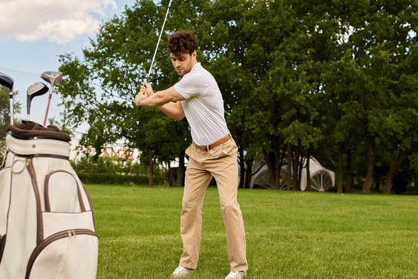 Een man slaat elegant een golfbal met een golftas in een groen veld, omringd door een luxe levensstijl. - Foto, afbeelding