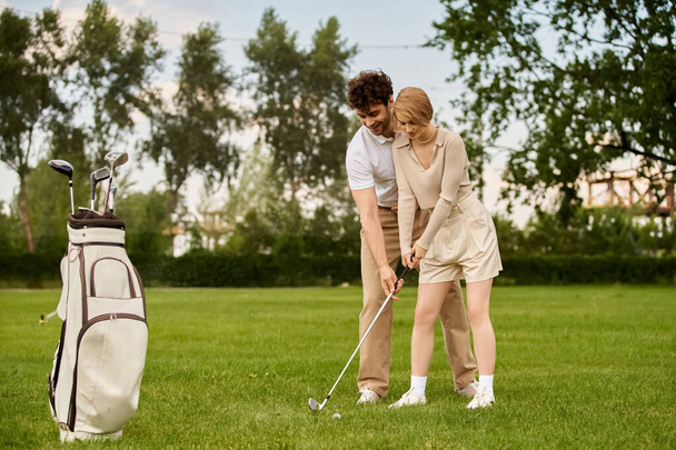 Bir adam ve bir kadın şık giyinmiş, golf sahasında golf oynuyorlar.. - Fotoğraf, Görsel