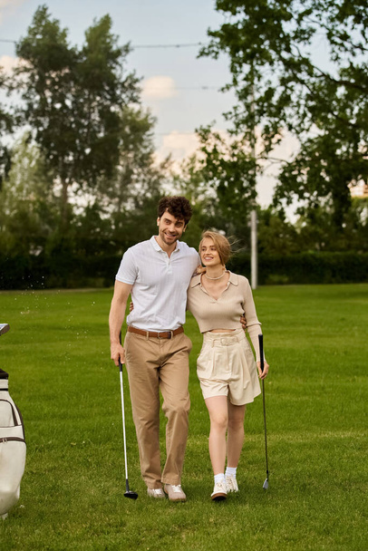 上流階級のライフスタイルの日差しに浸るゴルフコースをゆったり歩くスタイリッシュな若いカップル. - 写真・画像