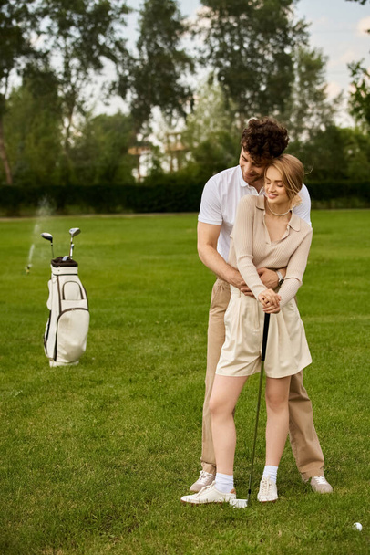 Молода пара в елегантному вбранні вражає позу на доглянутому майданчику незайманого поля для гольфу. - Фото, зображення