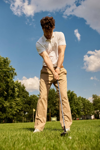 Стильный человек элегантно бьет мячом для гольфа по яркому, травянистому полю, олицетворяя очарование старинных денег высшего класса отдыха. - Фото, изображение