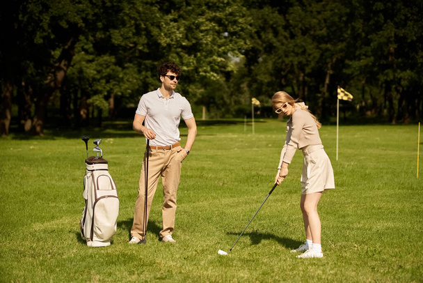 Стильный мужчина и женщина играют в гольф на нетронутом зеленом поле, воплощая в себе элегантность старых денег и стиль жизни высшего класса. - Фото, изображение
