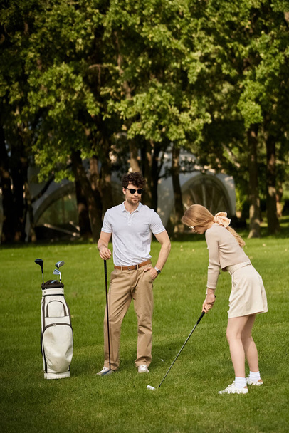 Ein junges Paar in eleganter Kleidung spielt Golf in einem üppig grünen Park. - Foto, Bild