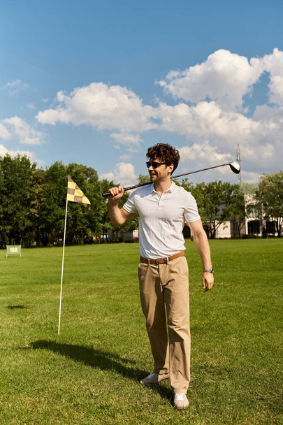 Ένας άνδρας με κομψή ενδυμασία παίζει γκολφ σε ένα καταπράσινο πεδίο, ενσωματώνοντας το κλασικό στυλ της άνεσης ανώτερης τάξης. - Φωτογραφία, εικόνα