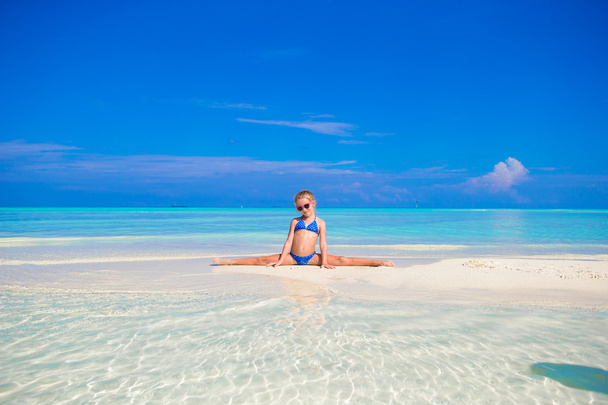Чарівна маленька дівчинка сидить на шипах на пляжі
 - Фото, зображення
