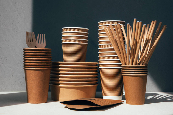Un conjunto de utensilios de papel y cubiertos de madera sobre un fondo gris. Concepto ecológico, cero residuos. Vista frontal - Foto, Imagen