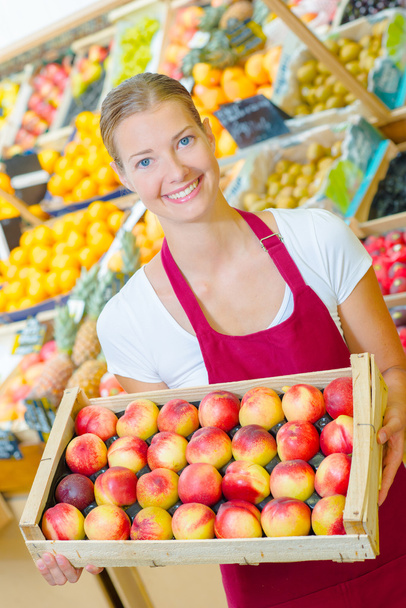 Shop assistant holding tray of nectarines - Fotoğraf, Görsel