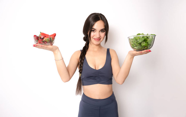 Fit woman eating healthy salad after working out isolated on white background. - Photo, Image