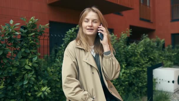 Porträt der stilvollen schönen Touristin sitzt auf Bank in der Stadtstraße, spricht mit ihrem Handy - Filmmaterial, Video