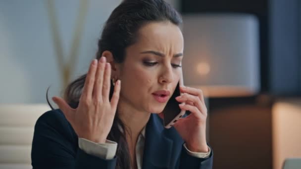 Напружена бізнес-леді розмовляє телефоном, жестикулюючи за столом крупним планом. Занепокоєна бізнес-леді, що розмовляє смартфоном на сучасному робочому місці, відчуває роздратування. Нервова жінка плутає телефонний дзвінок в офісі - Кадри, відео