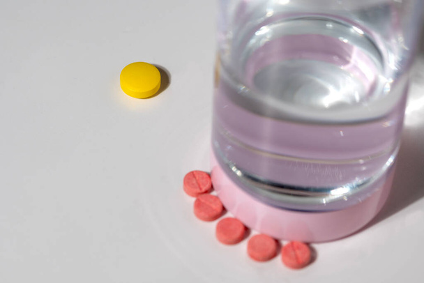 Барвисті таблетки і склянка води на білому тлі - Фото, зображення