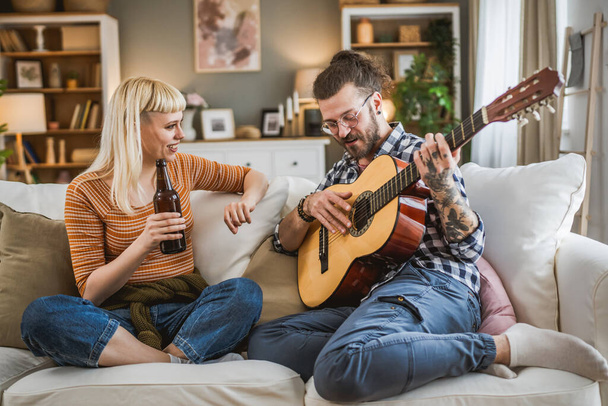 Adult couple enjoy at home play guitar and drink beer happy together - Photo, Image