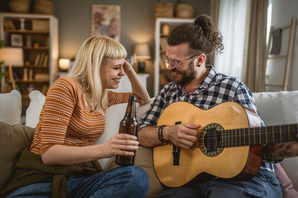 Coppia adulta godere a casa suonare la chitarra e bere birra felice insieme - Foto, immagini