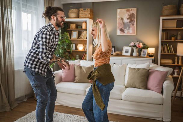 Una coppia adulta balla insieme e si diverte in soggiorno a casa - Foto, immagini