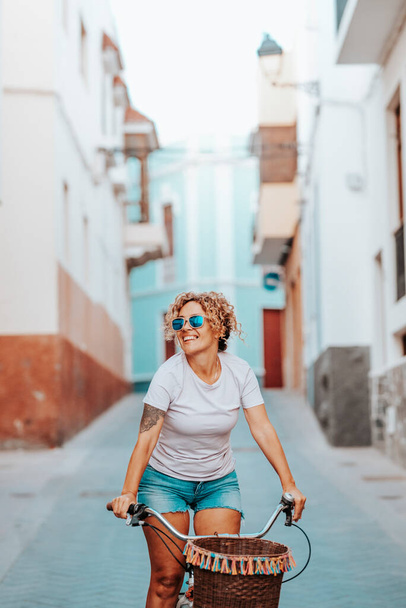 休暇中のバイク,魅力的で幸せな女性は,建築を調べる笑顔. 夏に自転車に乗る女性. 循環する女性のカーボンフットプリントを削減するための環境に優しい輸送 - 写真・画像
