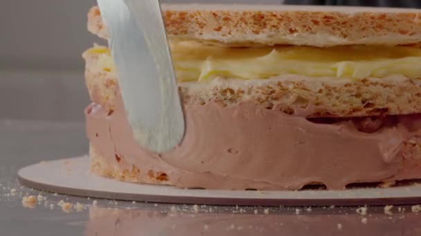 Culinar nanáší vzduchový krém na vrstvené koláče. Zavřít záběr zasklení vrstva coura. Přidávám více vanilkové omáčky na bocích dortu. Dělám měkké boky dortu s čokoládou. Vysoce kvalitní 4K záběry - Záběry, video