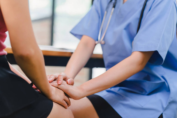 A nurse offers reassuring care by holding a patient's hand during a medical consultation, creating a supportive and empathetic atmosphere - Photo, Image